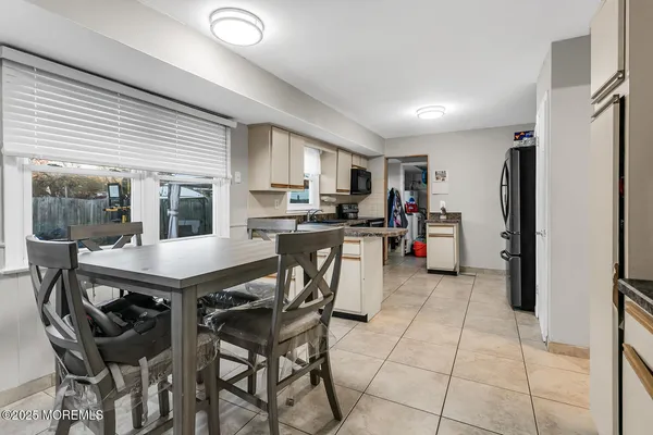 a kitchen with stainless steel appliances kitchen island granite countertop a refrigerator a stove a sink a dining table and chairs