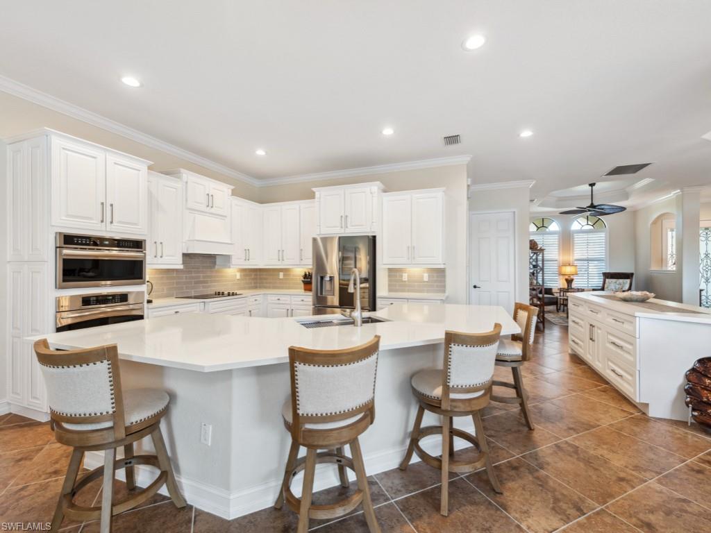 9430 Italia Way Naples, FL 34113 - Photo 10 of 47 Kitchen with a kitchen breakfast bar, a sink, appliances with stainless steel finishes, ceiling fan, and a large island with sink