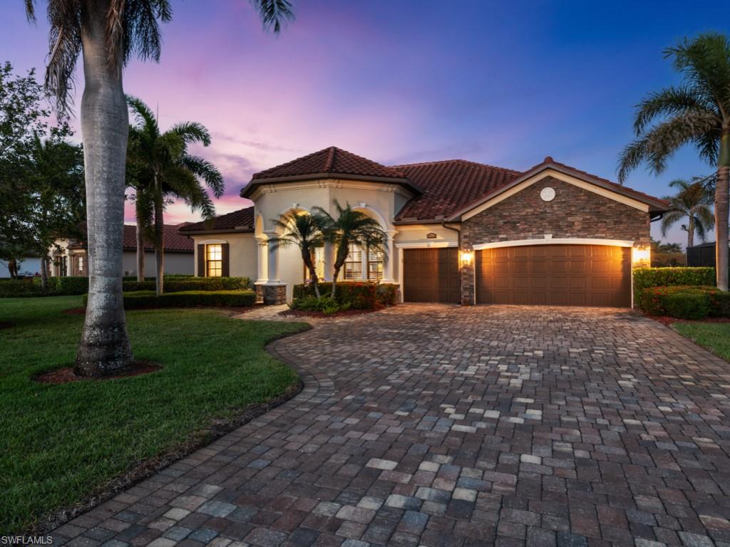 9430 Italia Way Naples, FL 34113 - Photo 2 of 47 Mediterranean / spanish house with stone siding, a tiled roof, decorative driveway, a lawn, and a garage