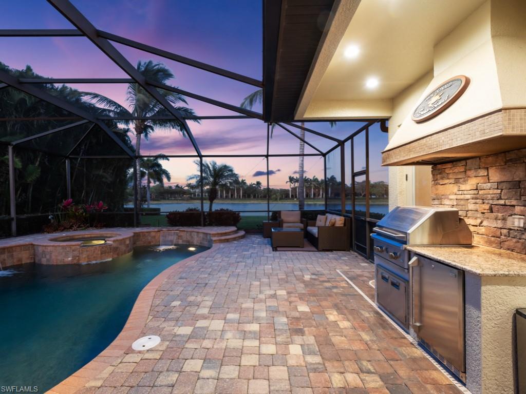 9430 Italia Way Naples, FL 34113 - Photo 31 of 47 View of patio with a water view, an outdoor hangout area, area for grilling, a pool with connected hot tub, and exterior kitchen