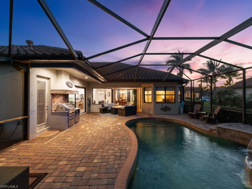 9430 Italia Way Naples, FL 34113 - Photo 32 of 47 Pool at dusk featuring a patio, an outdoor hangout area, an outdoor pool, exterior kitchen, and glass enclosure