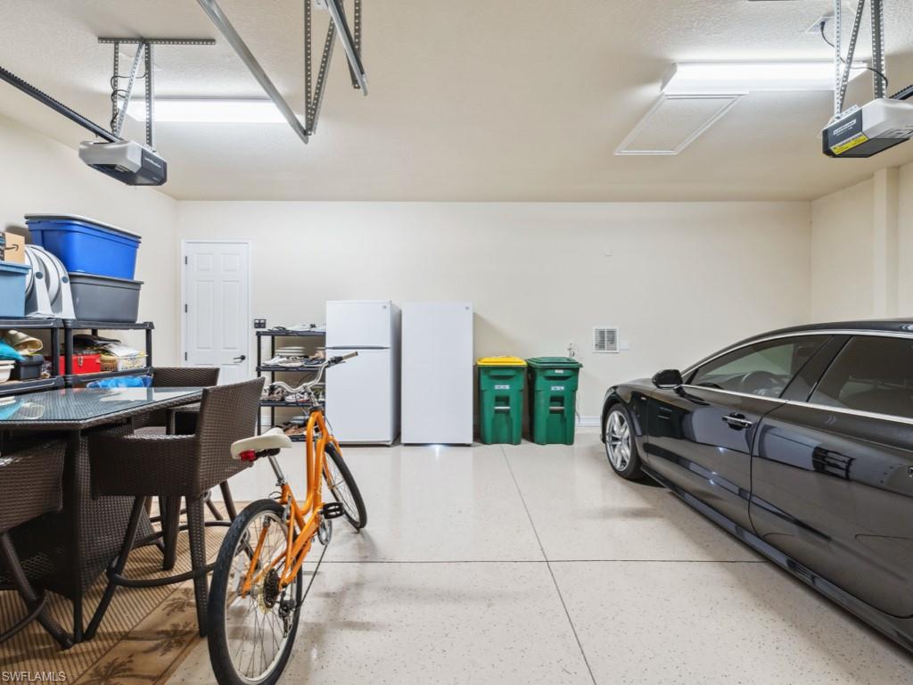9430 Italia Way Naples, FL 34113 - Photo 35 of 47 Garage with visible vents, freestanding refrigerator, and a garage door opener
