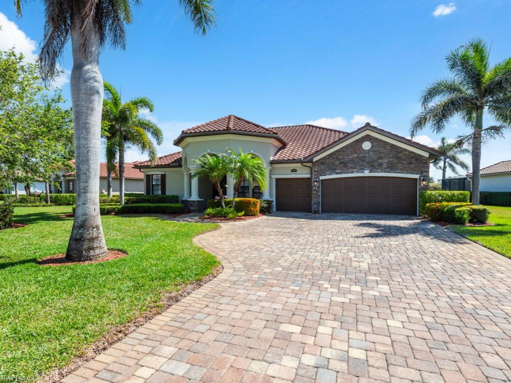 9430 Italia Way Naples, FL 34113 - Photo 4 of 47 Mediterranean / spanish house with stone siding, a tile roof, decorative driveway, a front yard, and a garage