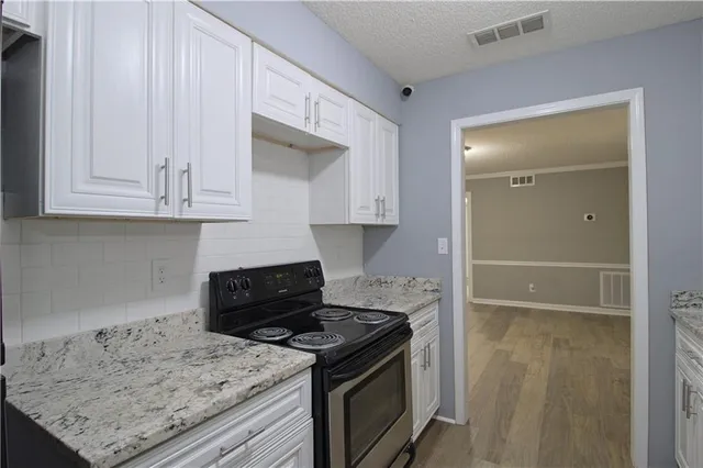 a kitchen with granite countertop a stove a sink and a white cabinets
