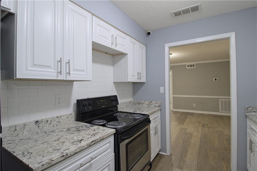 122 Rue Fontaine Lithonia, GA 30038 - Photo 12 of 36 a kitchen with granite countertop a stove a sink and a white cabinets