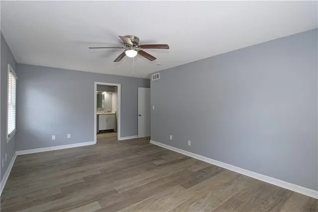 a view of empty room with wooden floor and ceiling fan