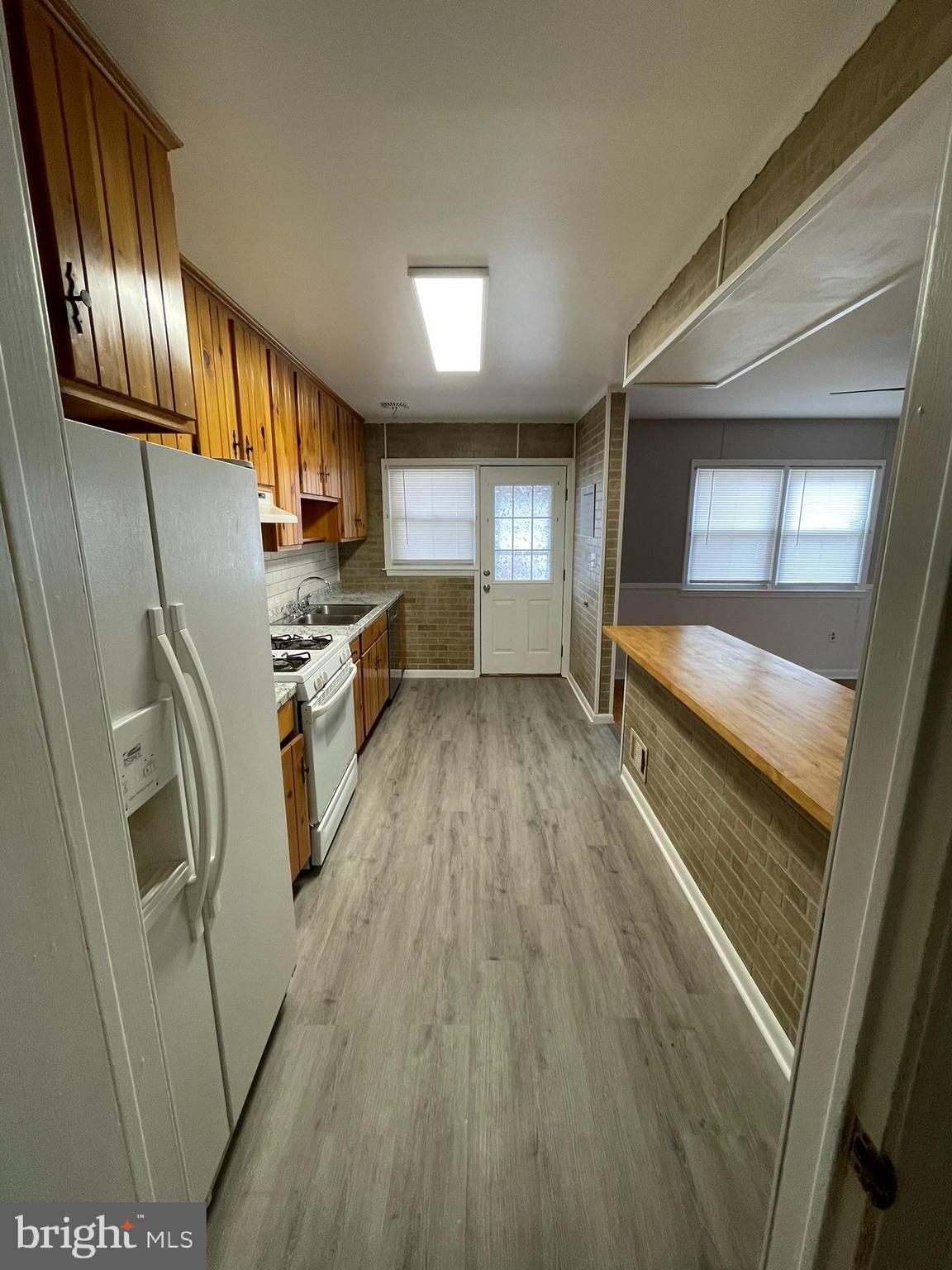 8134 Gray Haven Road Baltimore, MD 21222 - Photo 24 of 30 a kitchen with granite countertop a refrigerator a sink and dishwasher a stove top oven with wooden floor