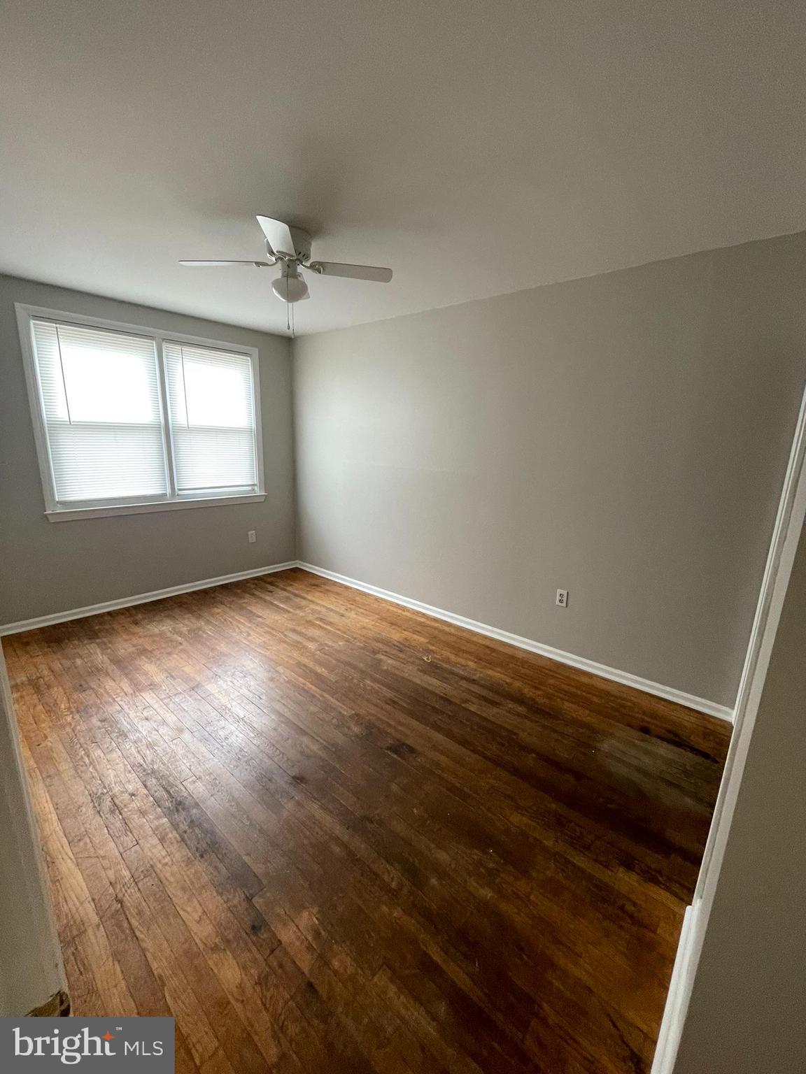 8134 Gray Haven Road Baltimore, MD 21222 - Photo 8 of 30 an empty room with wooden floor ceiling fan and windows