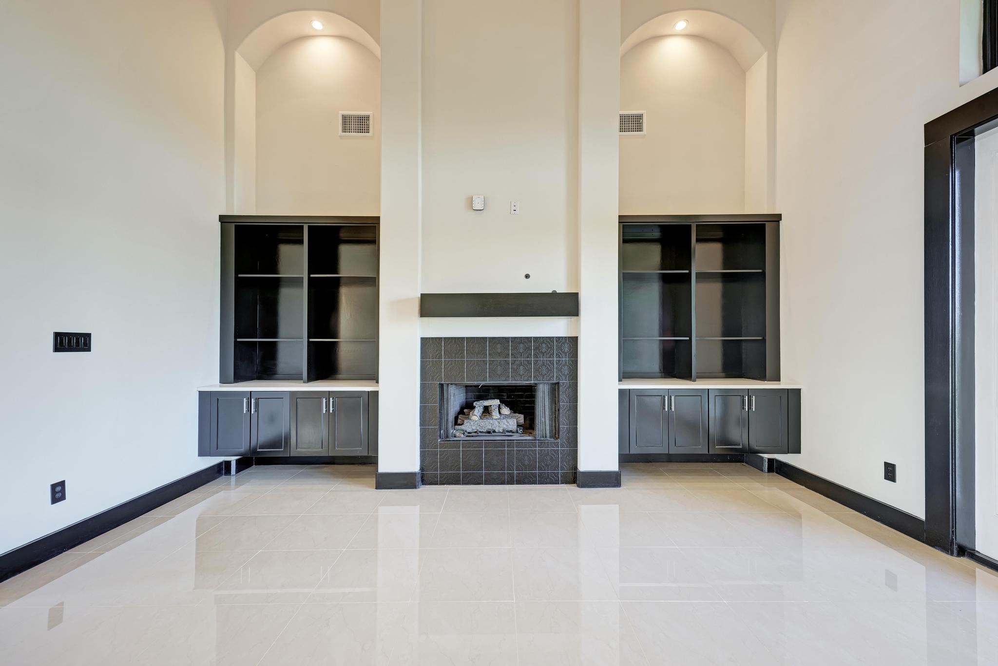 104 Spring Valley Street Hutto, TX 78634 - Photo 13 of 40 Unfurnished living room with a tiled fireplace, a towering ceiling, and light tile patterned floors
