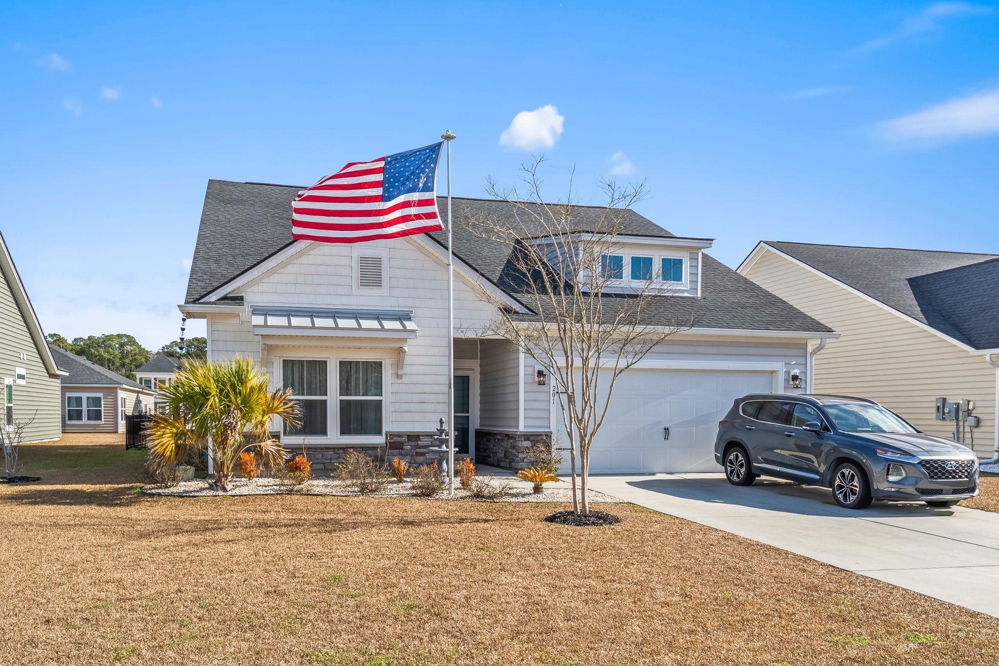 201 Craigflower Court Longs, SC 29568 - Photo 2 of 35 View of front of home featuring roof with shingles, driveway, stone siding, and a front yard