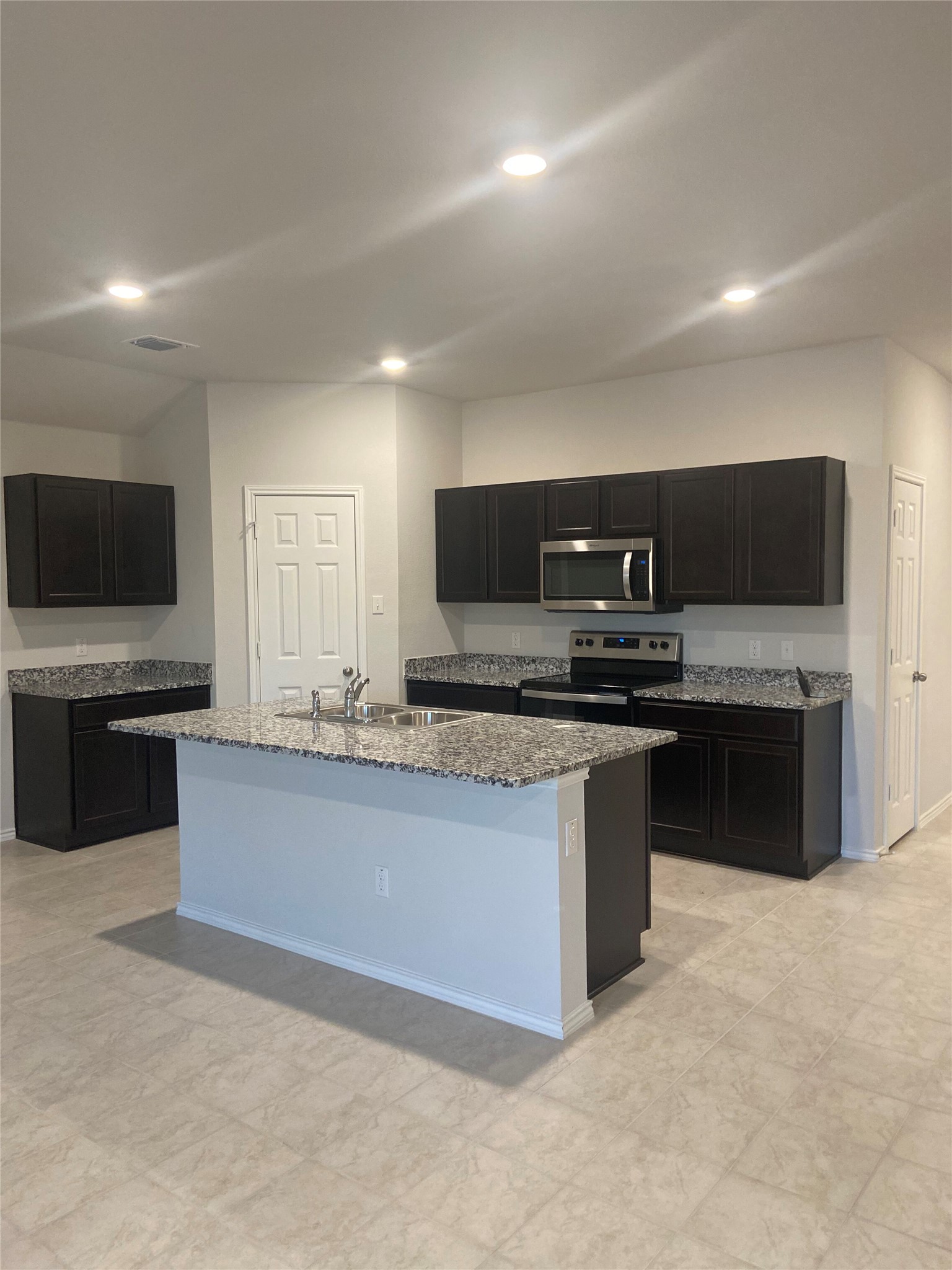 516 Taggart Trail Jarrell, TX 76537 - Photo 1 of 10 A well-appointed kitchen features dark cabinetry, ample counter space, and a functional island with a sink.