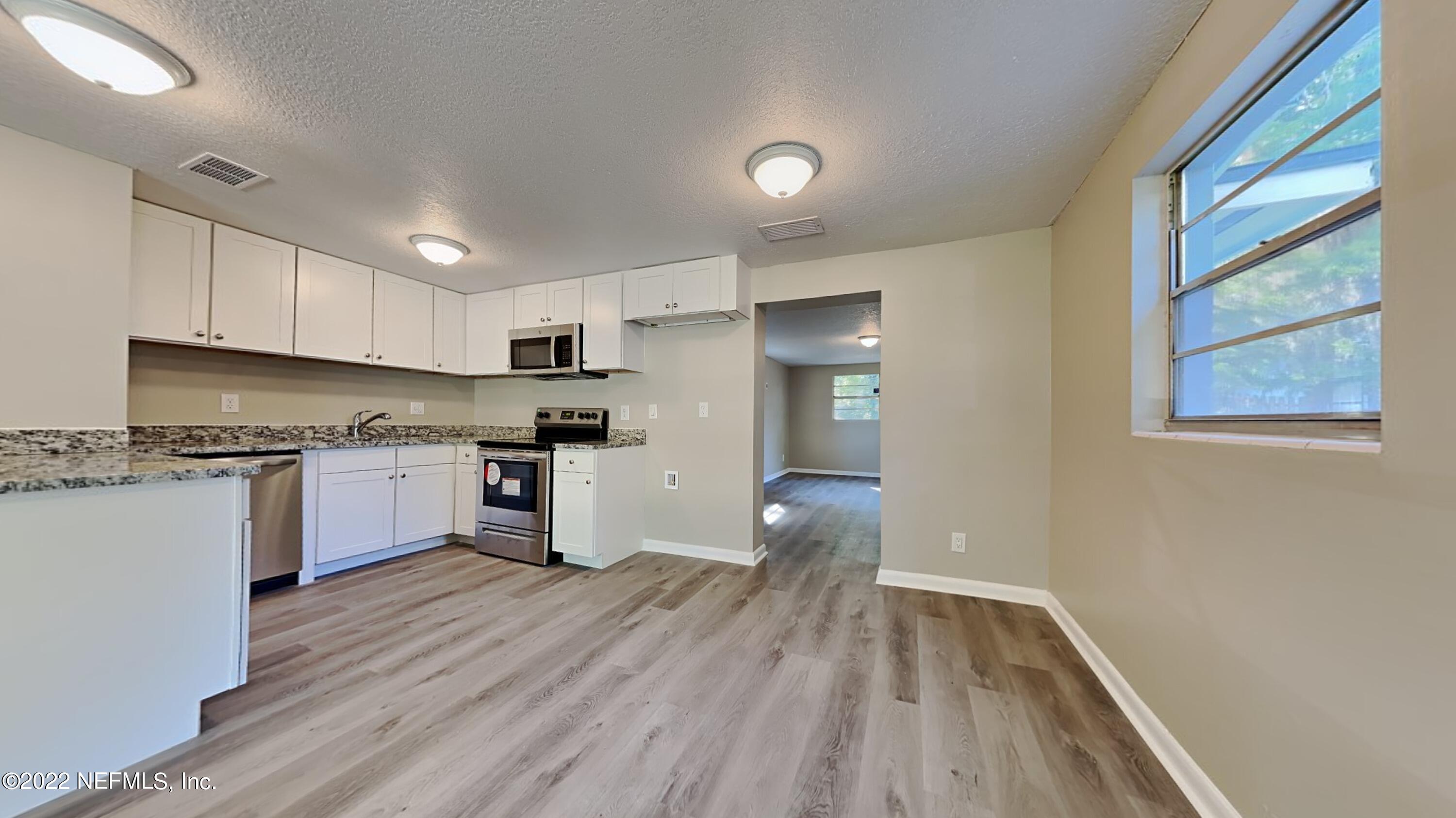 10729 Tulsa Road Jacksonville, FL 32218 - Photo 6 of 21 a kitchen with a refrigerator and white cabinets
