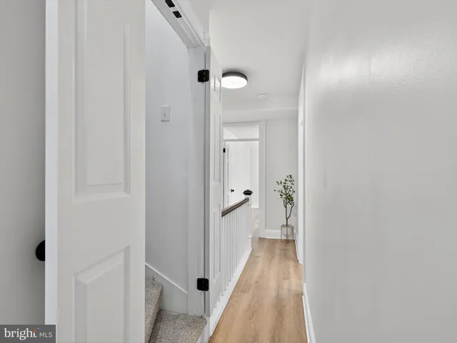 a view of a hallway with wooden floor and a bathroom