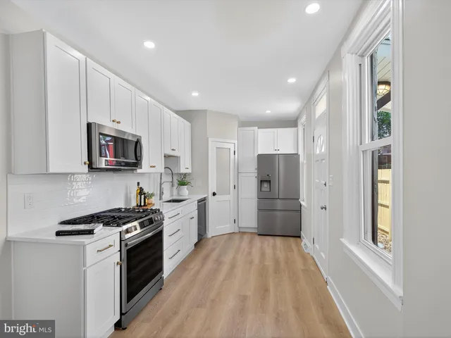 a kitchen with granite countertop a refrigerator and a stove top oven