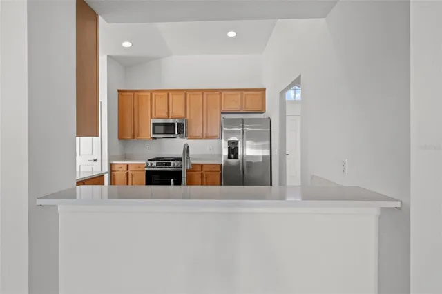 a large kitchen with stainless steel appliances a large counter top a stove and a refrigerator