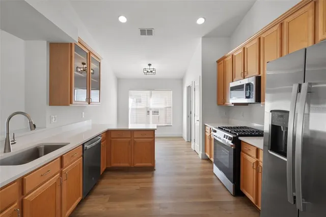 a large kitchen with stainless steel appliances granite countertop a stove refrigerator and a sink with wooden cabinets