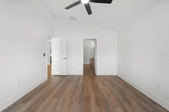an empty room with wooden floor cabinet and windows