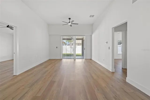 a view of an empty room with wooden floor and a window