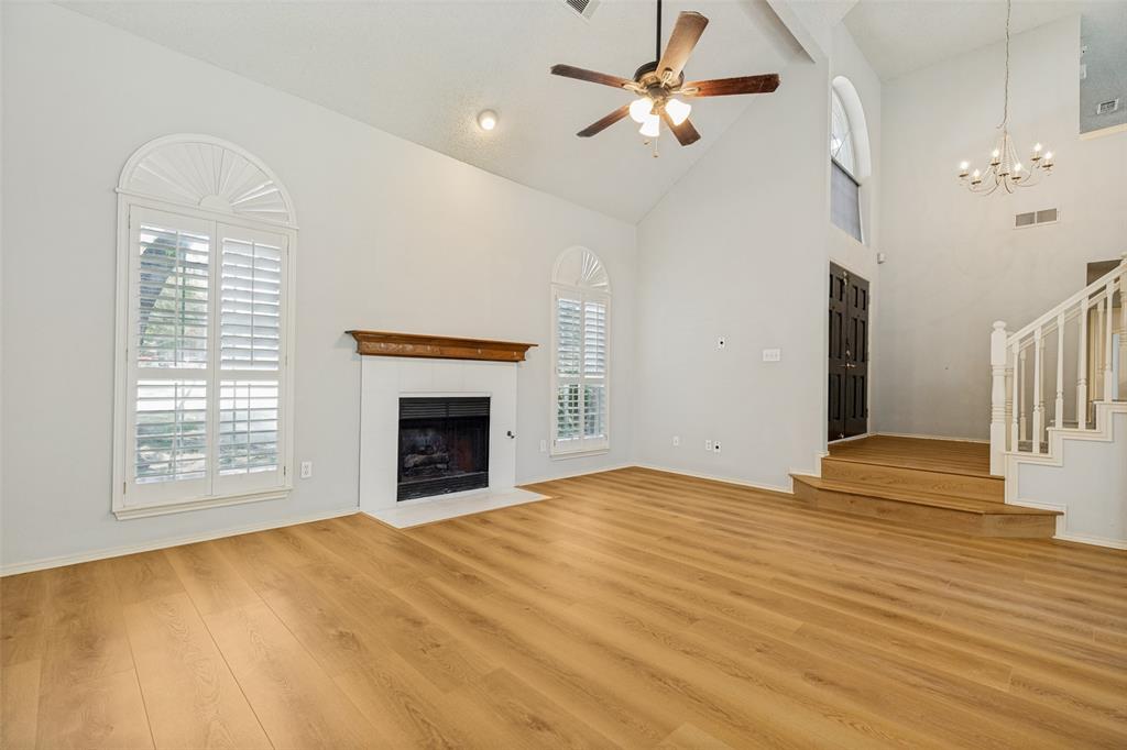 1215 Spring Creek Drive Allen, TX 75002 - Photo 4 of 40 Spacious living area featuring high vaulted ceilings, light wood-finish flooring, and a fireplace with a wood mantel