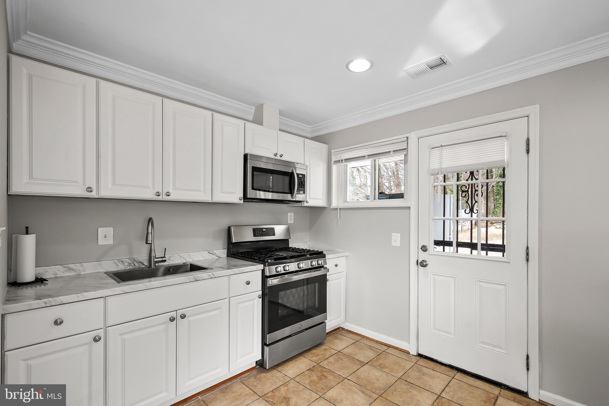 1204 Lindsay Road Oxon Hill, MD 20745 - Photo 11 of 28 a kitchen with white cabinets stainless steel appliances and sink