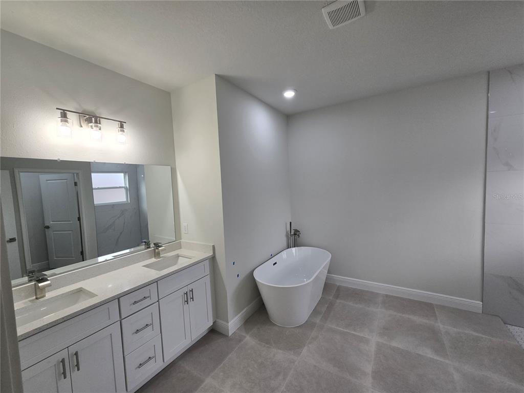 2717 Southwest 140th Loop Ocala, FL 34473 - Photo 20 of 40 a spacious bathroom with a double vanity sink a toilet and a bathtub