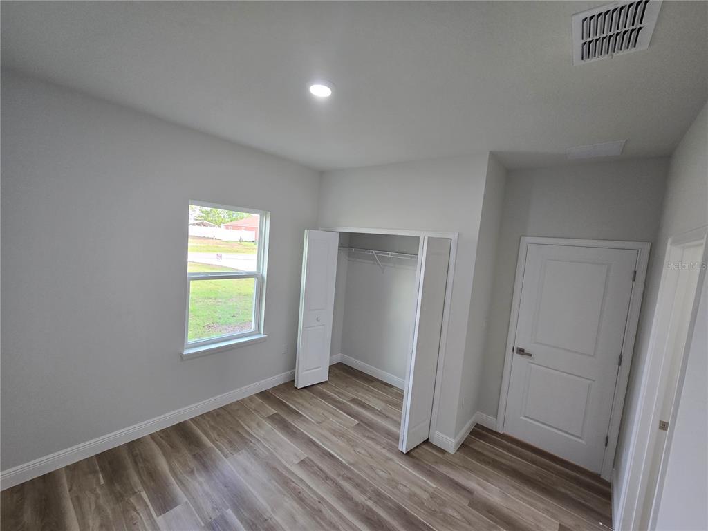 2717 Southwest 140th Loop Ocala, FL 34473 - Photo 33 of 40 an empty room with wooden floor closet and windows