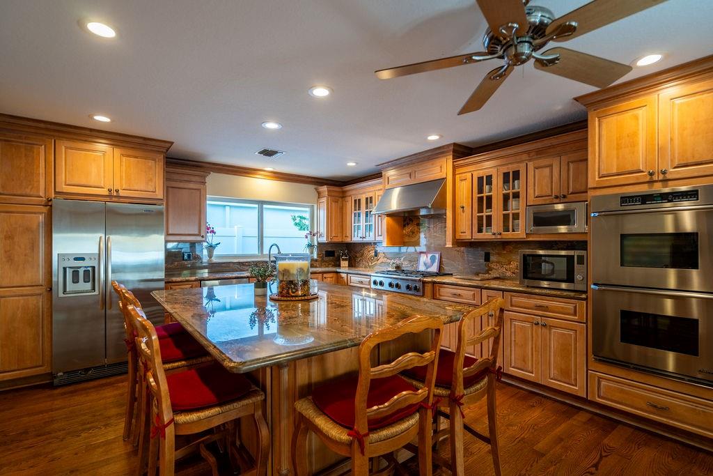 2317 Northeast 28th Court Lighthouse Point, FL 33064 - Photo 16 of 49 a kitchen with stainless steel appliances granite countertop a dining table chairs refrigerator and microwave
