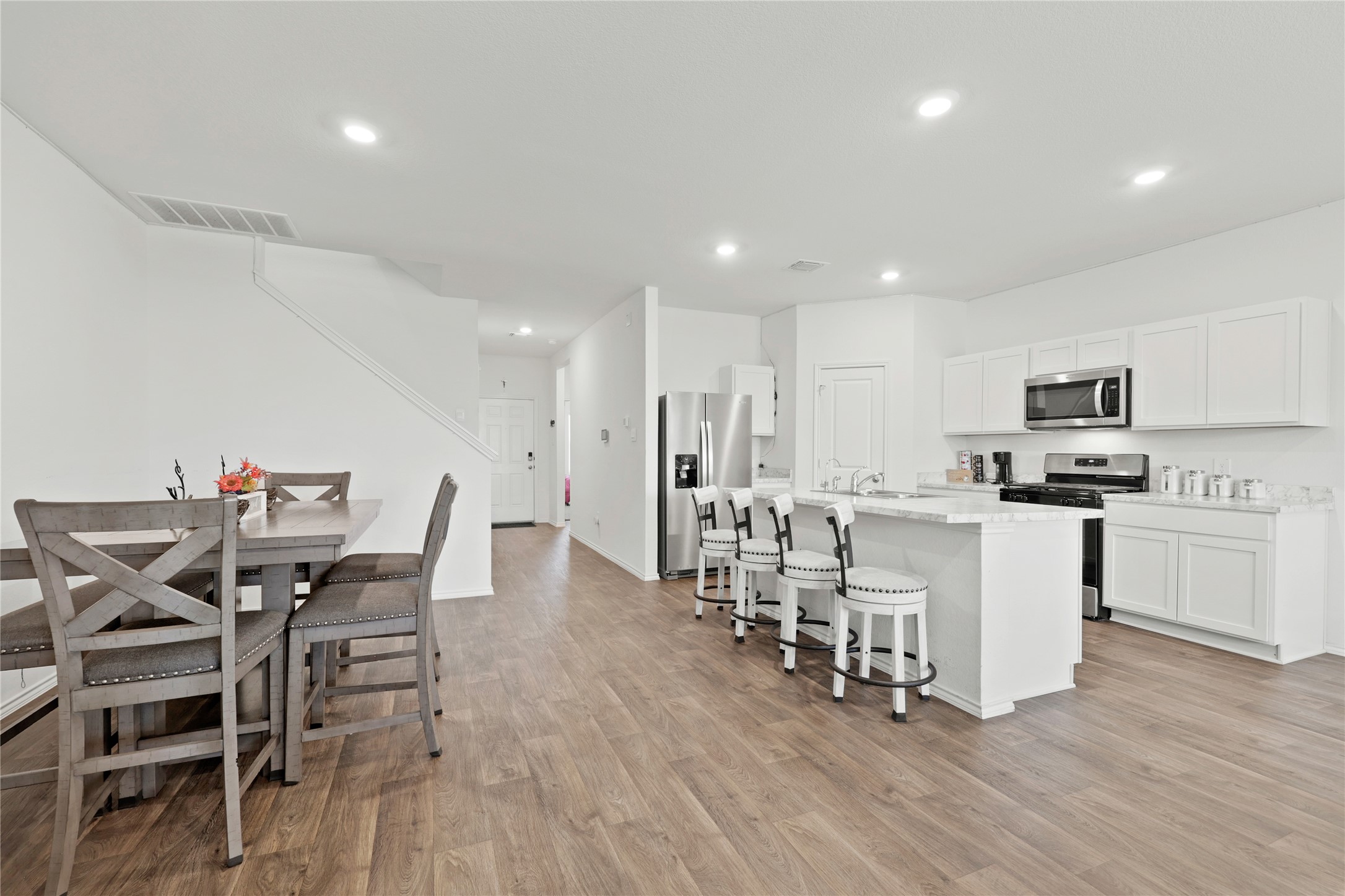 790 Arnold Loop Kyle, TX 78640 - Photo 12 of 36 Enjoy the ultimate open-concept layout where the sleek kitchen and spacious dining area meet, featuring gorgeous wood-style flooring and bright recessed lighting that keeps the energy high throughout the day.