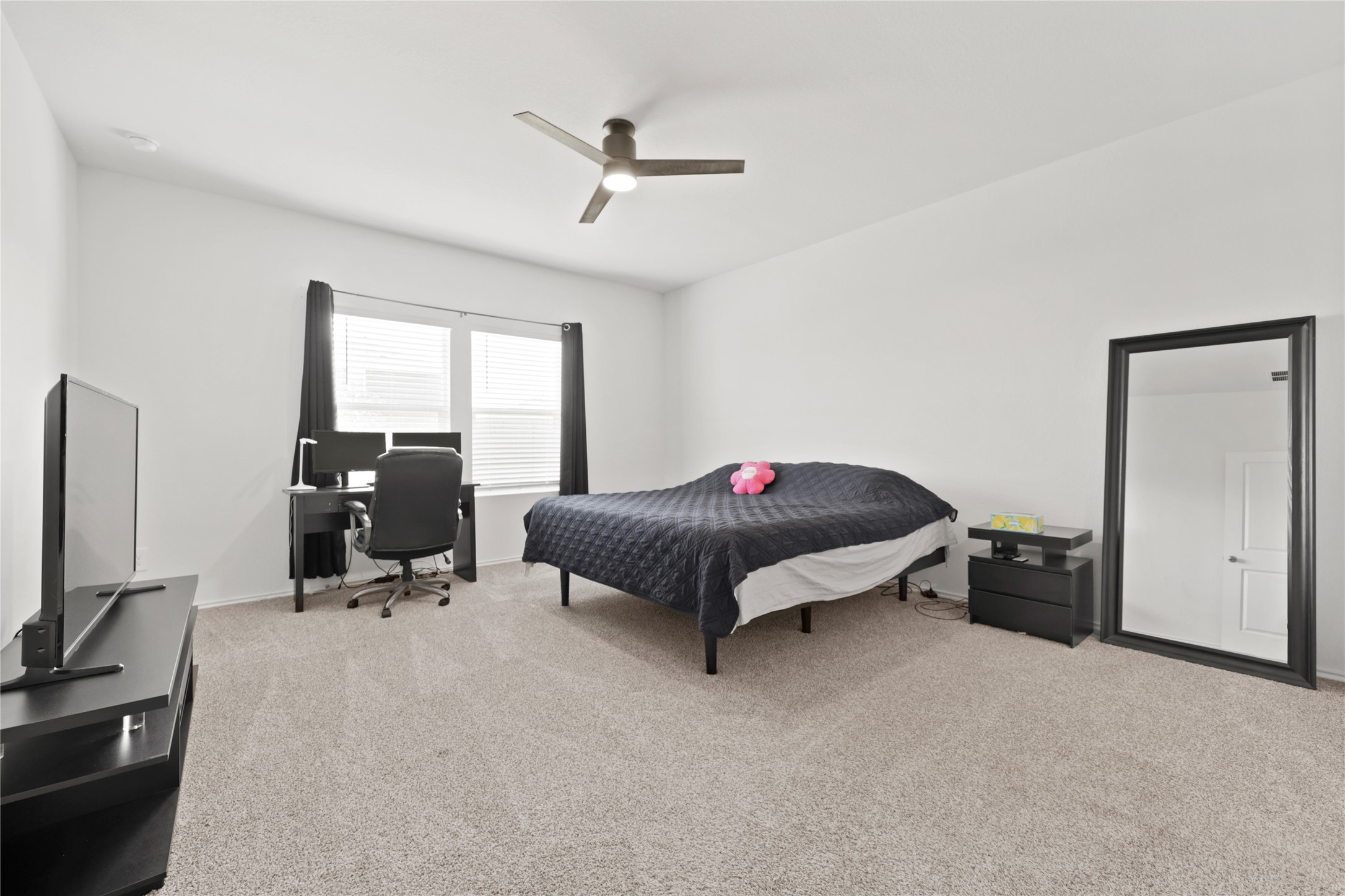 790 Arnold Loop Kyle, TX 78640 - Photo 16 of 36 Your private sanctuary! This expansive primary bedroom is a true retreat, featuring plush carpeting, a cooling ceiling fan, and enough space for a king-sized bed plus a full executive home office setup.