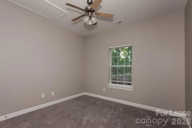an empty room with a window and a fan