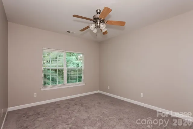 an empty room with a window and a fan