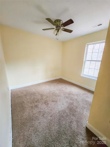 an empty room with windows and fan