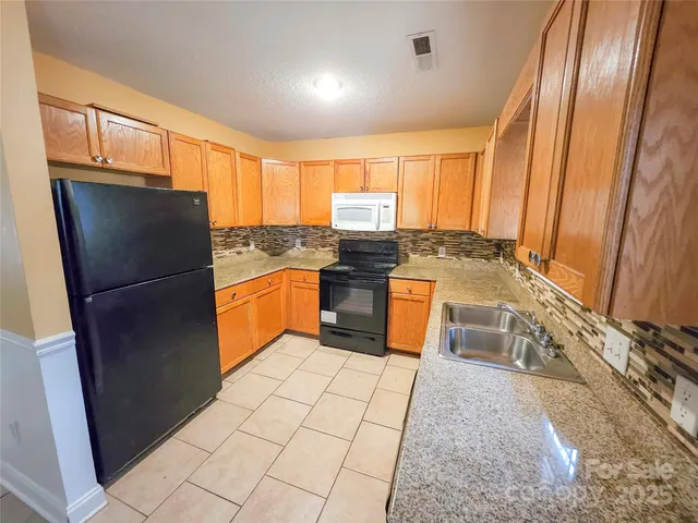 a kitchen with stainless steel appliances granite countertop a refrigerator a stove a sink and a microwave