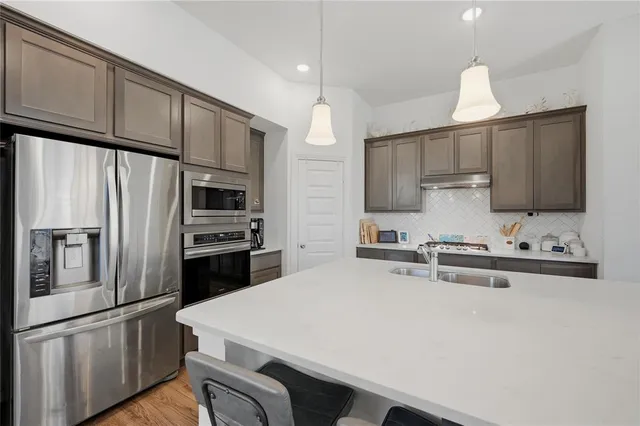 a kitchen with a sink a counter top space a large window and stainless steel appliances