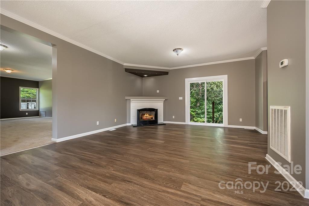 6410 Big Level Road Mill Spring, NC 28756 - Photo 7 of 32 an empty room with wooden floor fireplace and windows