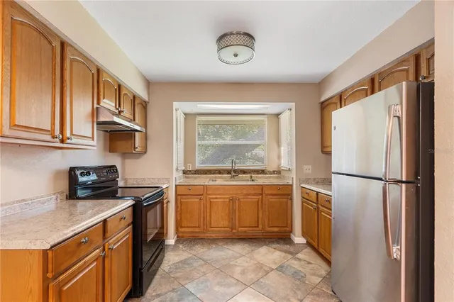a kitchen with stainless steel appliances granite countertop a refrigerator a stove and a sink with wooden floor