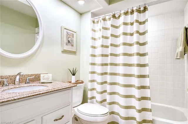 a bathroom with a granite countertop toilet a sink and a mirror