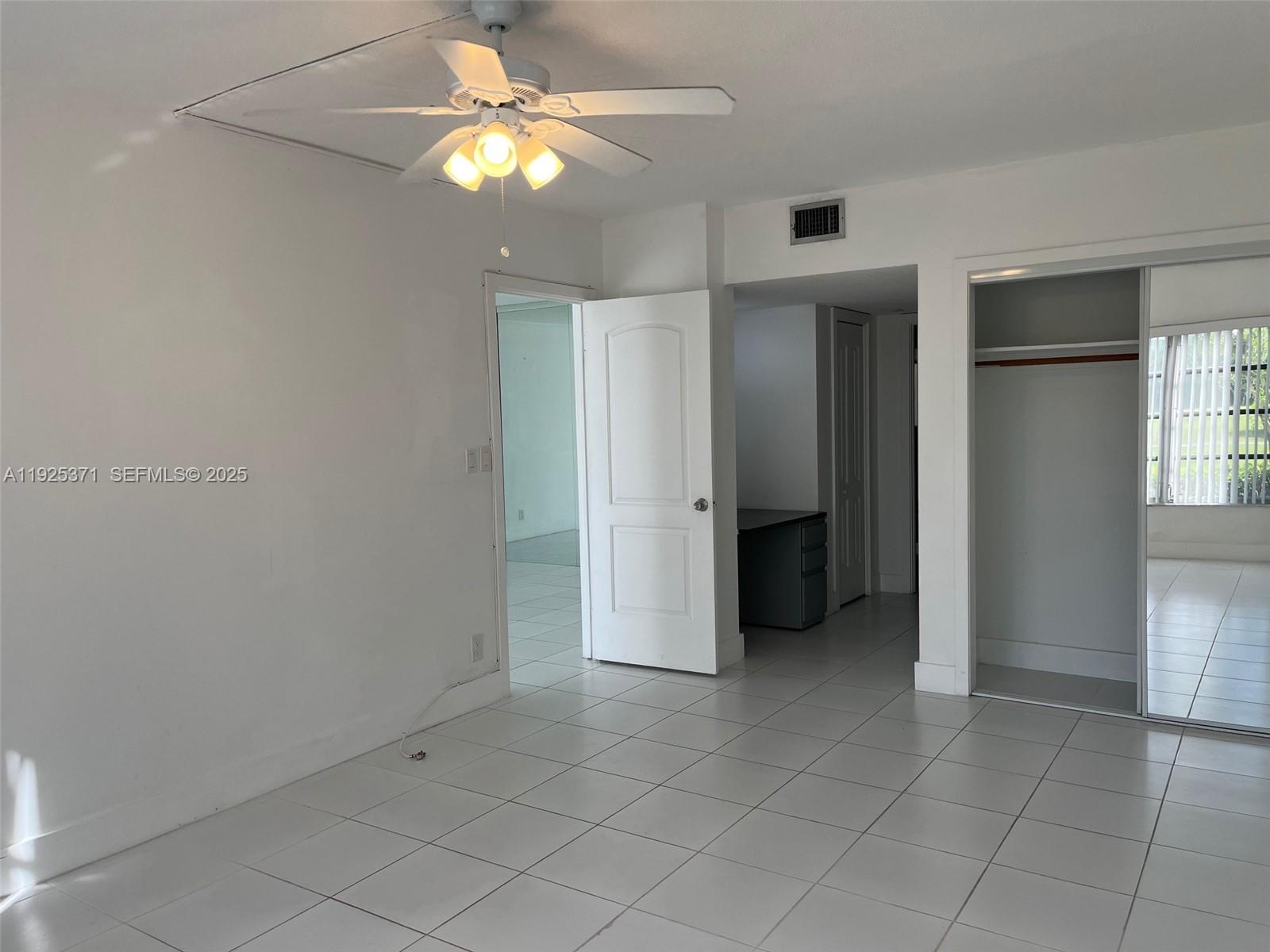 3100 North Palm Aire Drive, Unit 104 Pompano Beach, FL 33069 - Photo 16 of 20 en empty room with closet and a chandelier fan