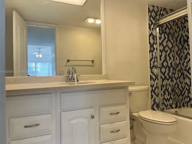 a bathroom with a granite countertop toilet sink and mirror