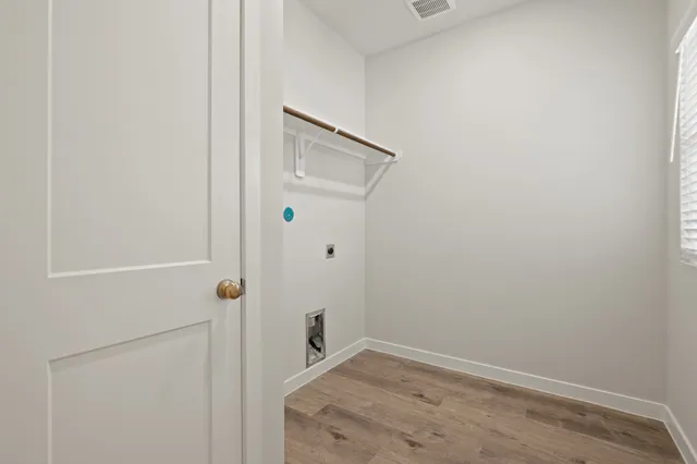 an empty room with wooden floor chandelier fan and windows