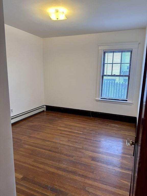 289 Highland Avenue, Unit 1L Quincy, MA 02170 - Photo 4 of 5 an empty room with wooden floor and windows