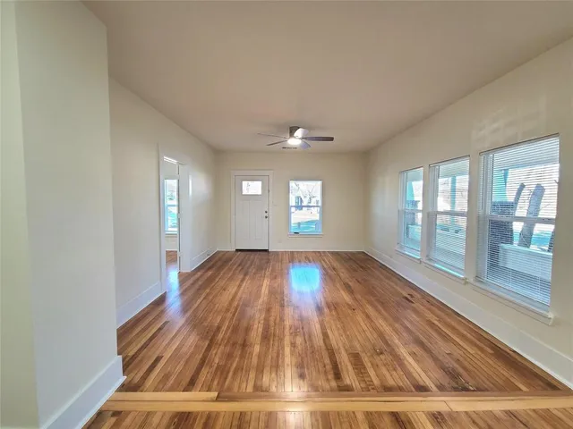 a view of empty room with wooden floor and fan