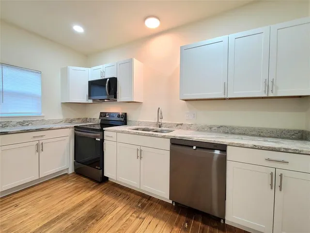 a kitchen with granite countertop a sink cabinets and stainless steel appliances