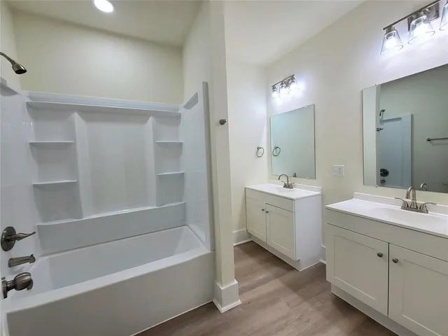 a bathroom with a double vanity sink mirror and bathtub