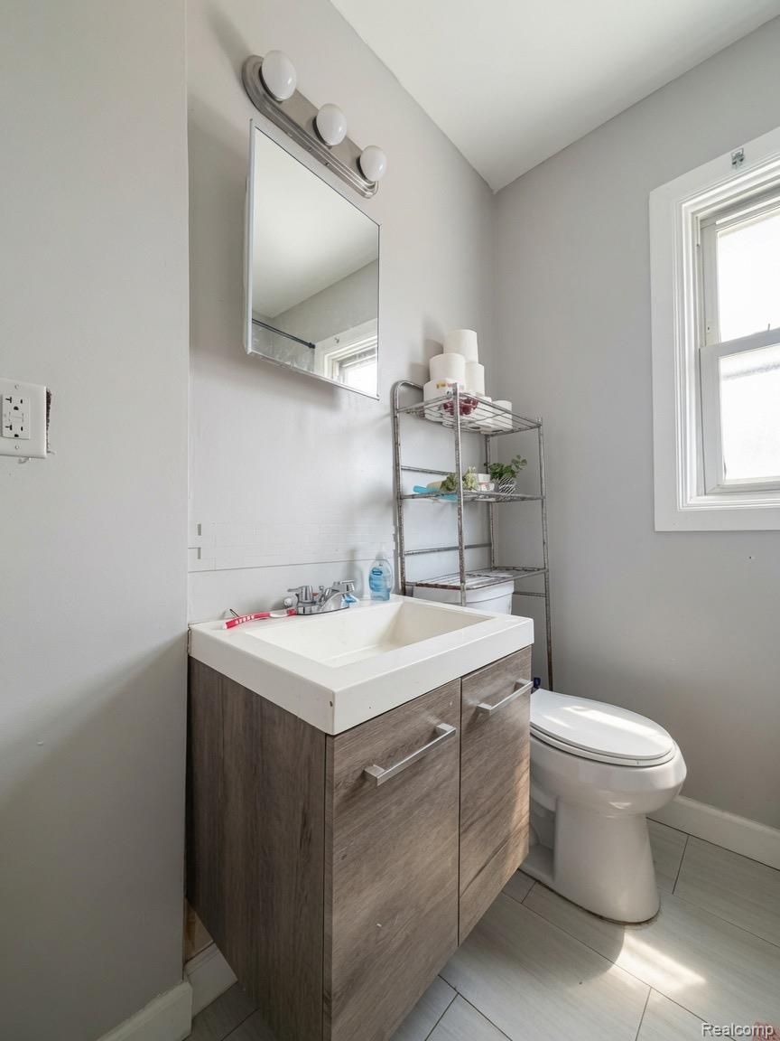 9940 Manor Detroit, MI 48204 - Photo 8 of 16 Bathroom featuring a wood-finish vanity with an integrated sink, a wall-mounted mirror, and a three-bulb vanity light fixture