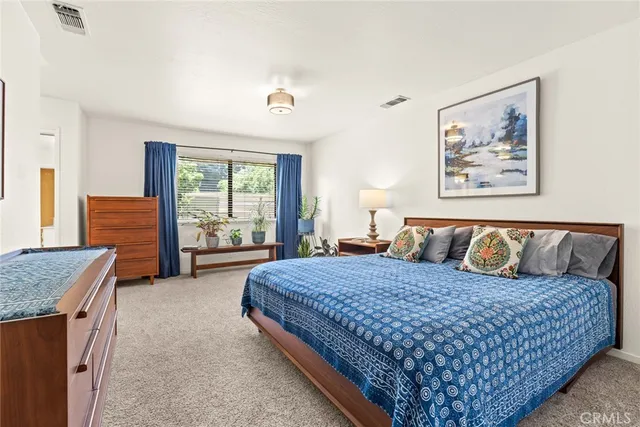 a large bedroom with a large bed and a flat tv screen on dresser
