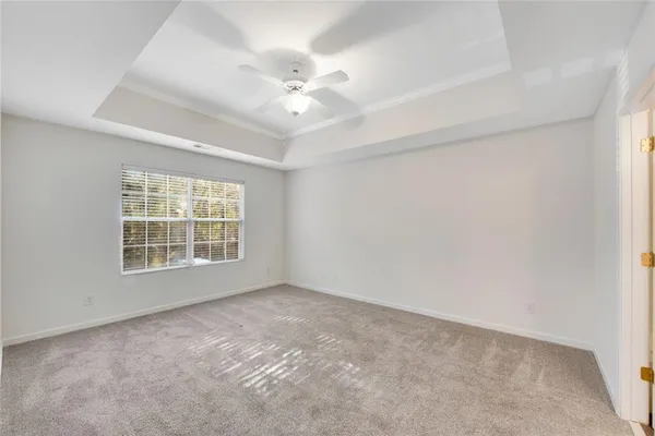 an empty room with a chandelier fan and windows