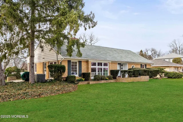 a front view of a house with a garden and trees