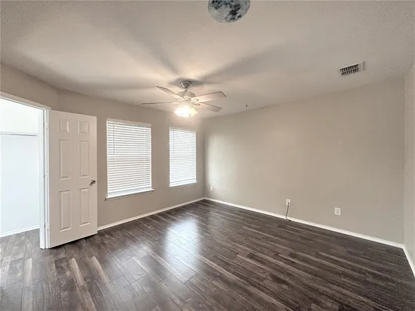 an empty room with wooden floor and windows