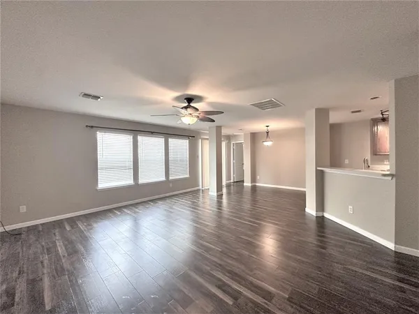 a view of a livingroom with wooden floor and a kitchen